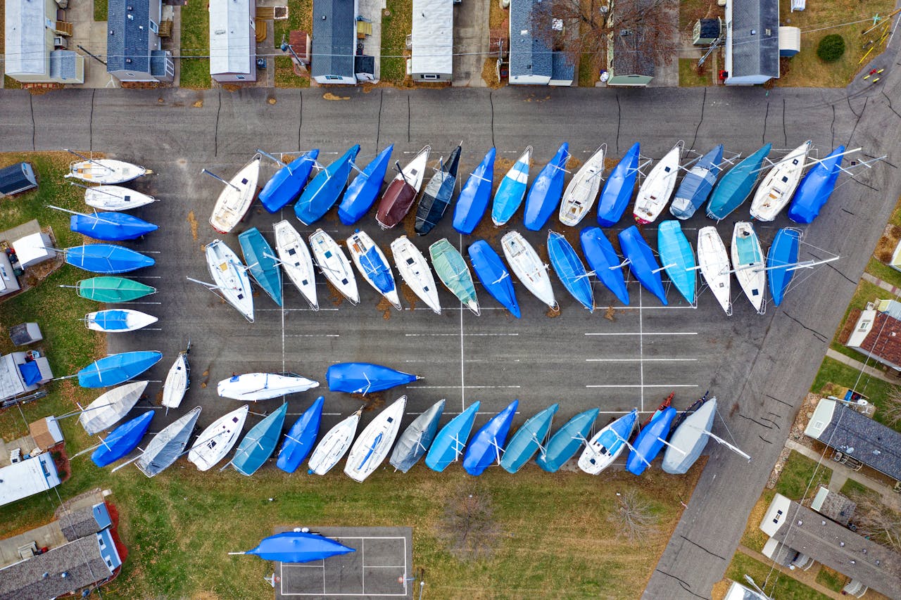 services-04 Aerial shot of numerous sailboats covered with blue tarps in an urban marina parking area.
